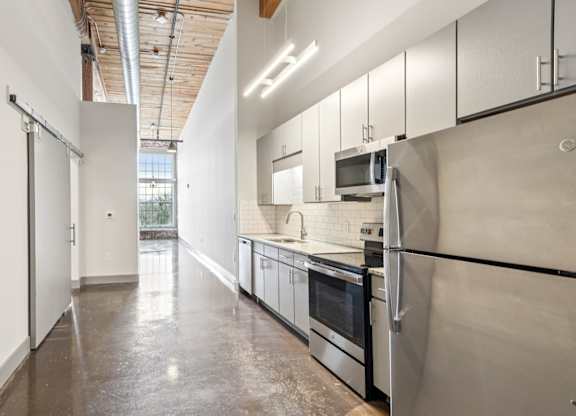 Kitchen and hallway at Converse Mill Lofts in Spartanburg, SC with stone floor and stainless steel appliances