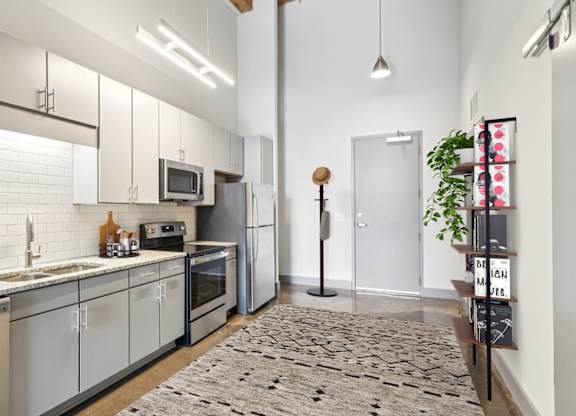 Vitually staged kitchen with stainless steel appliances, granite countertops, gray cabinetry and stone floors in Converse Mill Apartments in Spartanburg, SC.