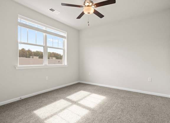 A room with a ceiling fan and a window letting in sunlight.