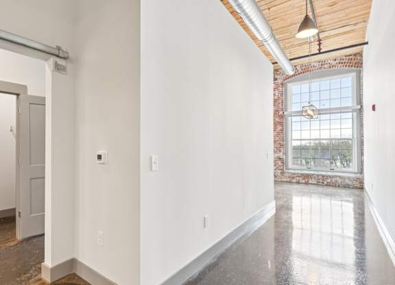 Hallway in apartments in Converse Mill Loft Apartments in Spartanburg, SC with large ceilings, brick walls and exposed beams on ceiling.