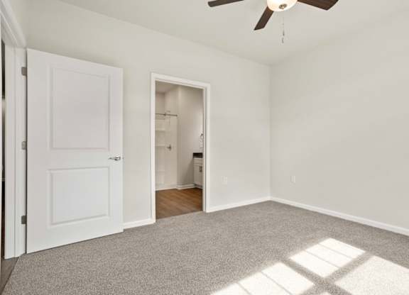 A room with a ceiling fan and a door.