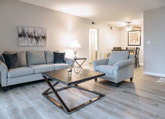 A living room with a grey couch, a coffee table, and a painting on the wall.
