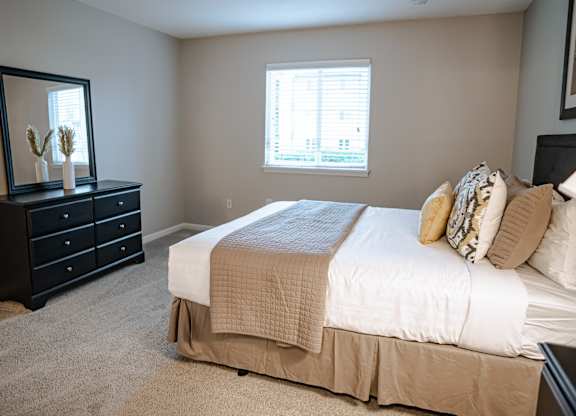 A bedroom with a bed, dresser, and mirror.