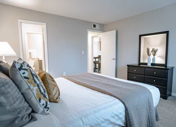 A bedroom with a bed, dresser, and mirror.