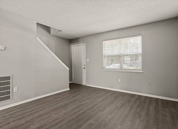 A room with a staircase and a window with blinds.