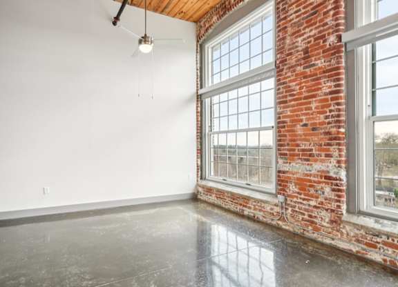 Living room with high ceilings and large windows at Converse Mill Loft Apartments in Spartanburg, SC