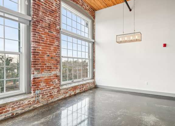 Living room with high ceilings and large windows at Converse Mill Loft Apartments in Spartanburg, SC
