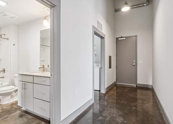 Hallway with stone floors, bathroom and in-unit washer and dryer at Converse Mill Lofts in Spartanburg, SC.