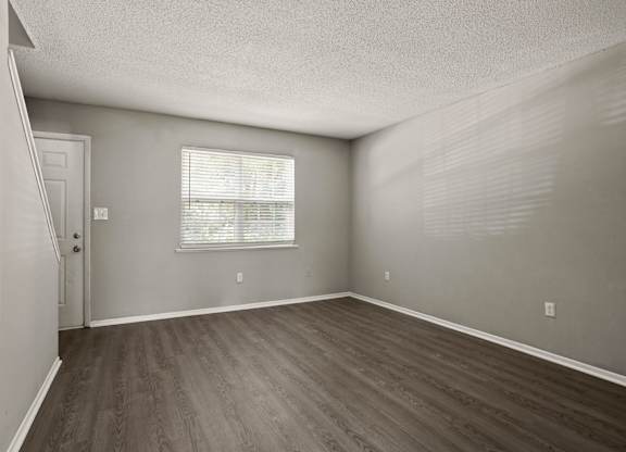 A room with wooden flooring and a window with blinds.