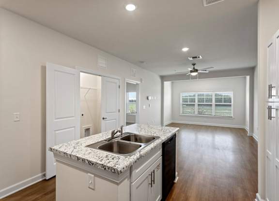 Peaks of Lexington Apartments Kitchen with Black Appliances, Granite Countertops and White Cabinetry and connected living room