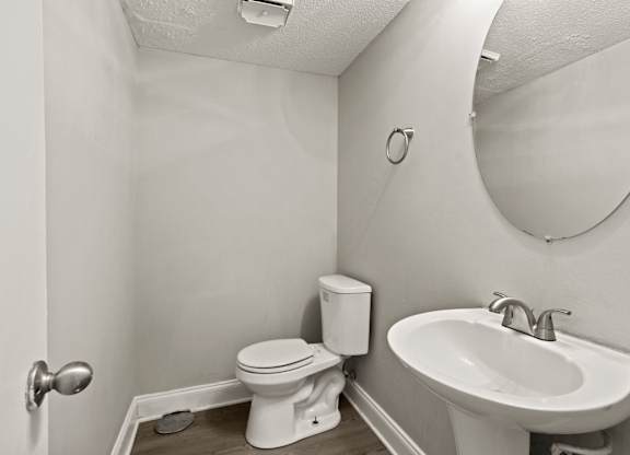 A bathroom with a toilet, sink and mirror.