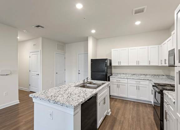 Peaks of Lexington Apartments Kitchen with Black Appliances, Granite Countertops and White Cabinetry and connected living room