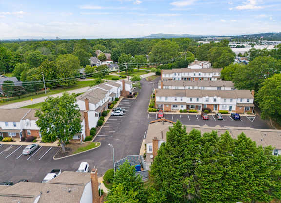 A bird's eye view of a parking lot with cars and buildings.