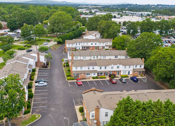 A parking lot in front of a building surrounded by trees.