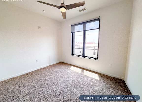 A second bedroom with a ceiling fan and carpeted floor.
