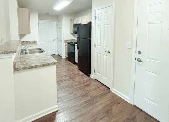 Brookside Gardens kitchen with black appliances, brown floors and granite countertops
