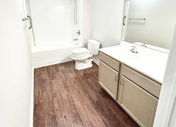 Brookside Gardens bathroom with a bath, shower, white sink, hardwood floors, a mirror and a toilet.