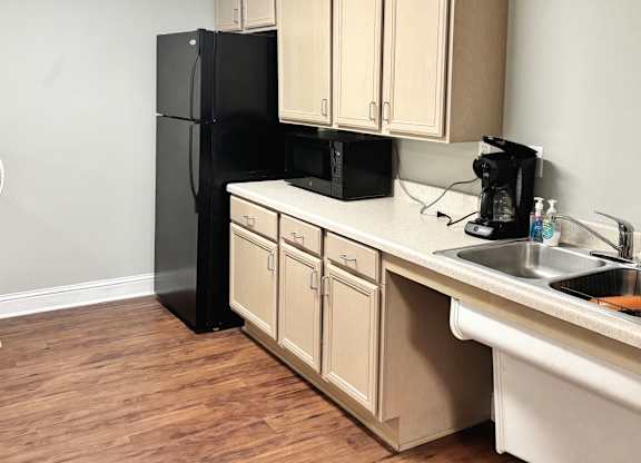 Brookside Gardens community kitchen with black refrigerator, cabinets and sink