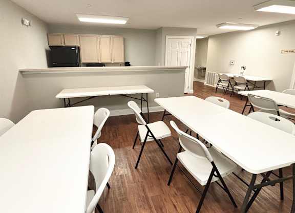 A room with tables and chairs and a black television.