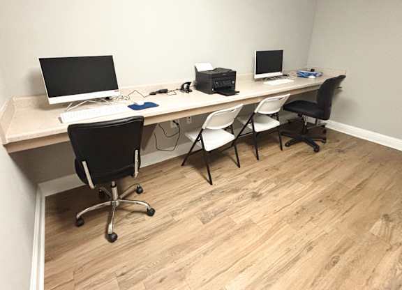 A room with a desk and chairs with a computer on it.