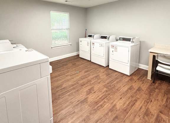 A room with white appliances and wooden flooring.