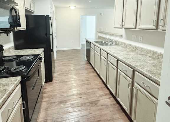 A kitchen with black appliances and white cabinets.