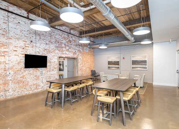 Converse Mill Lofts Apartments Community Room with tables, chairs and a TV