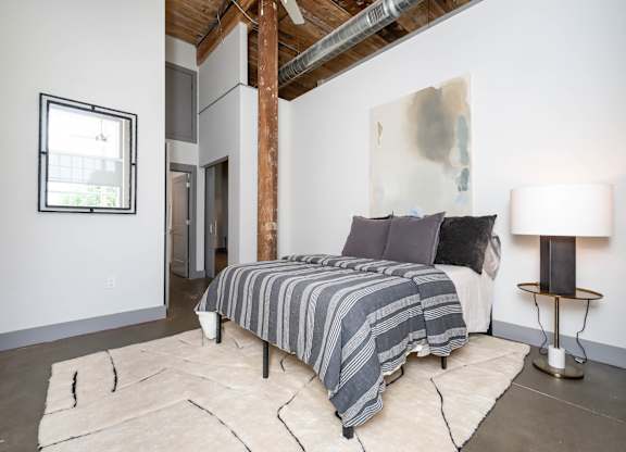 Converse Mill Lofts Luxury Apartments Model Unit Staged Bedroom with high ceilings, exposed beams