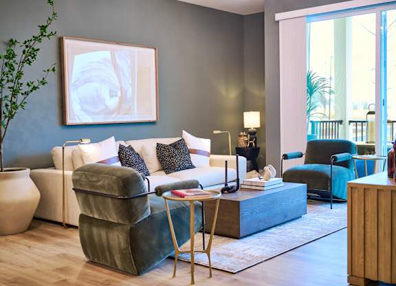 A living room with a white couch, a green chair, and a large painting on the wall.