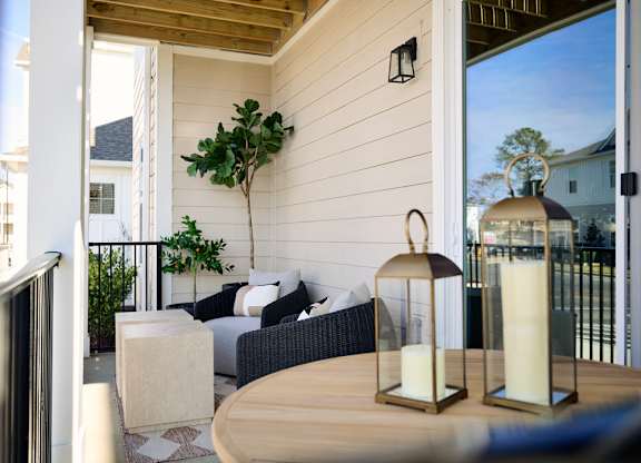 A patio with a table, chairs, and lanterns.