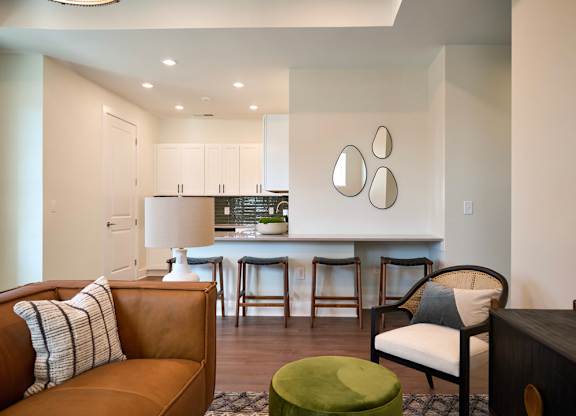 A living room with a brown couch and a green ottoman.