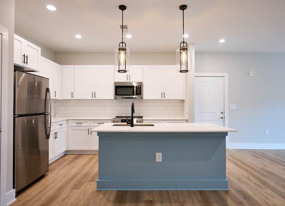A kitchen with a blue island and stainless steel appliances.