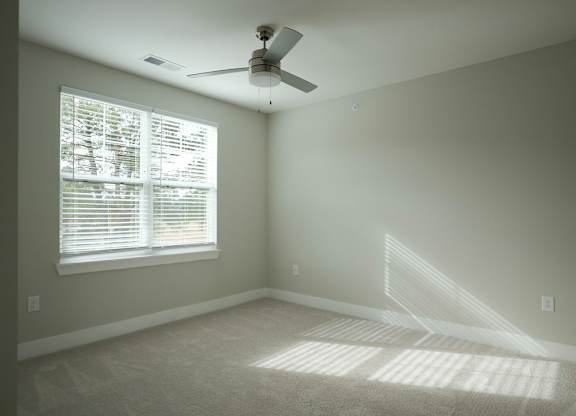 A room with a ceiling fan and a window with blinds.