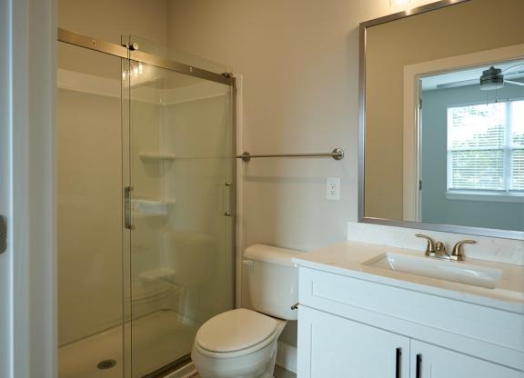 A white bathroom with a toilet, sink, and shower.