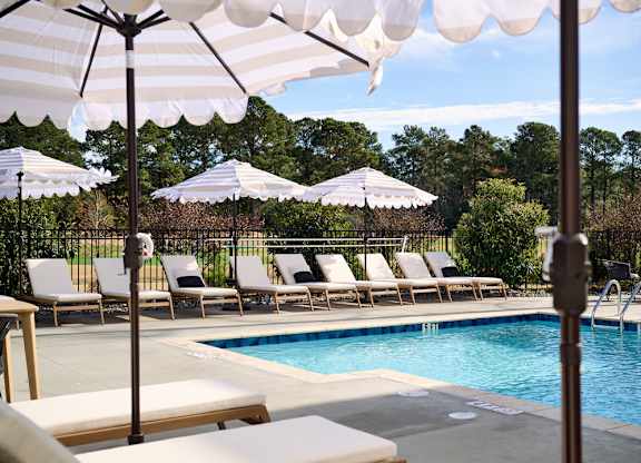 A pool with a white canopy and lounge chairs.