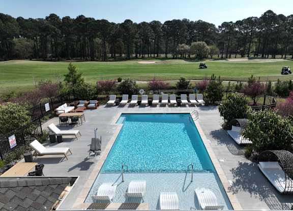 A large swimming pool surrounded by lounge chairs and trees.