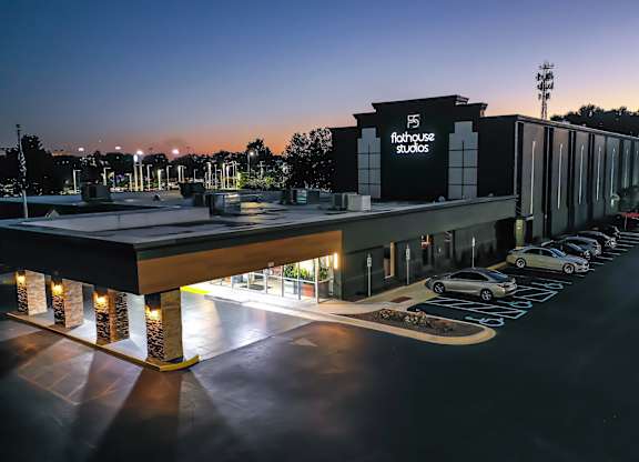 A parking lot is in front of a building with the sign Flathouse Studios.