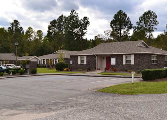 A building with a red door is surrounded by a parking lot.