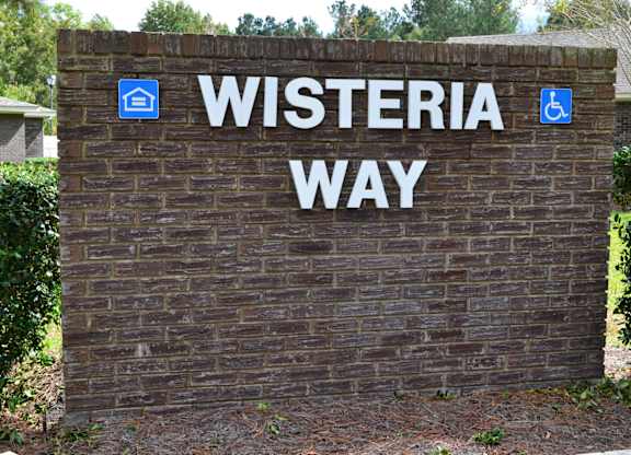 A sign that says Wisteria Way with a wheelchair and a house symbol.