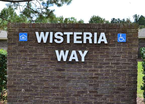 A sign that says Wisteria Way in front of a building.