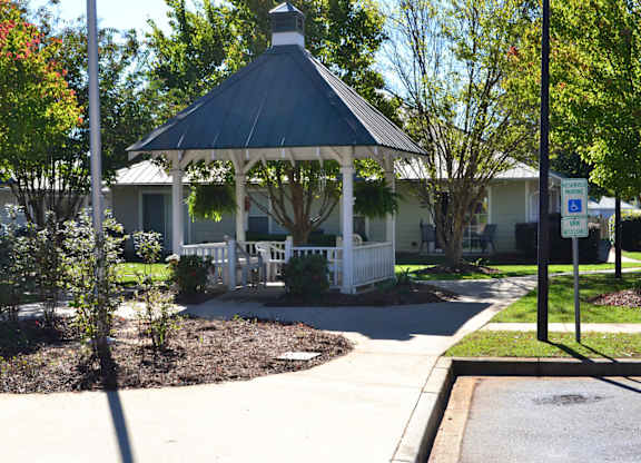 A gazebo is surrounded by a white picket fence.