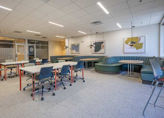 A room with tables and chairs and a whiteboard.