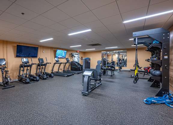 A gym with a variety of exercise equipment including treadmills, stationary bikes, and weight machines.