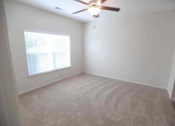 A room with a ceiling fan and a window with blinds.
