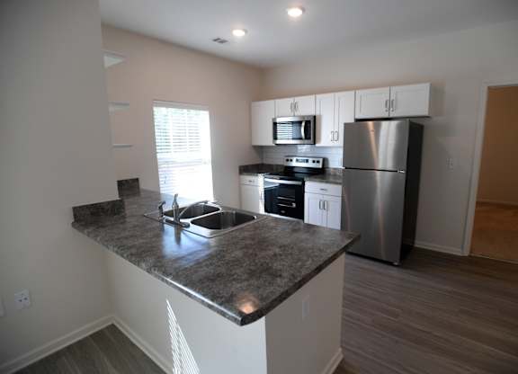 A kitchen with a granite countertop and stainless steel appliances.