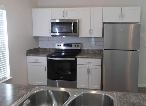 A kitchen with a stainless steel refrigerator, microwave, oven, and sink.