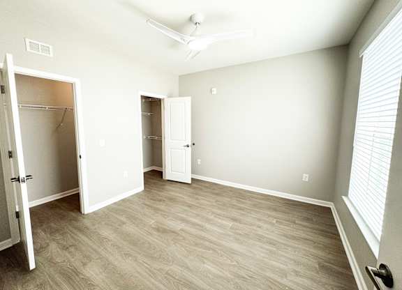 A room with a white door and a white closet with a white ceiling fan.