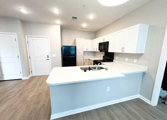 A kitchen with a white island and black appliances.