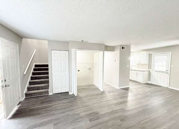 Reserve at Hillcrest living room with LVT flooring, washer and dryer hookups, bathroom, kitchen, closet and carpeted stairs.