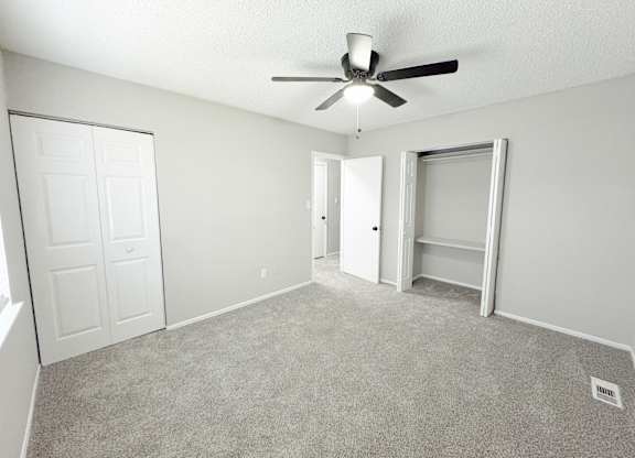 Reserve at Hillcrest Townhomes bedroom with two closets, gray carpet, and a ceiling fan with a light